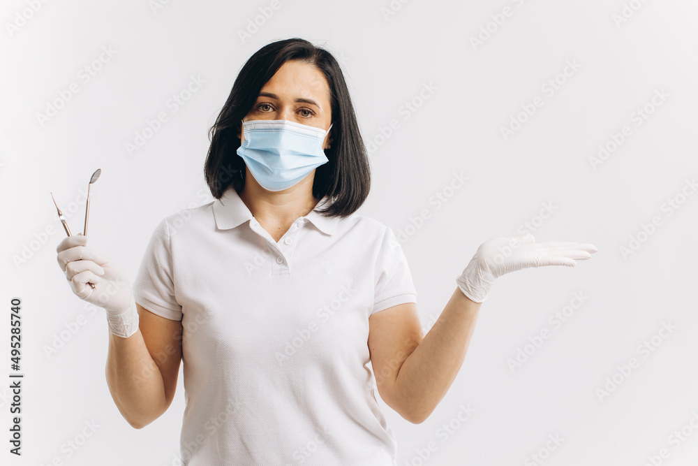 Woman dentist in a medical mask shows something on a copy space. Woman dentist in a medical mask shows something on a copy space.