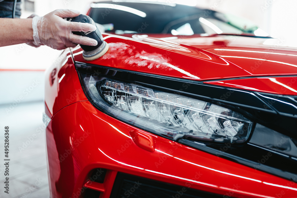 Car detailing - Worker with orbital polisher in auto repair shop. Car detailing - Worker with orbital polisher in auto repair shop.