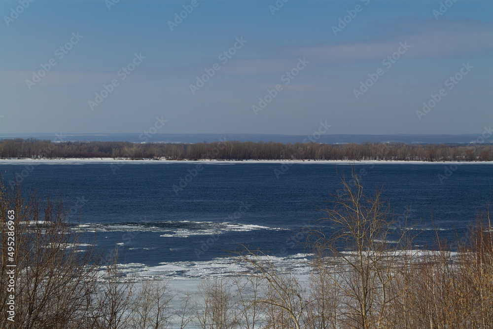 river in spring. landscape of winter forest with sunlight and snow. blue river with ice and snow.