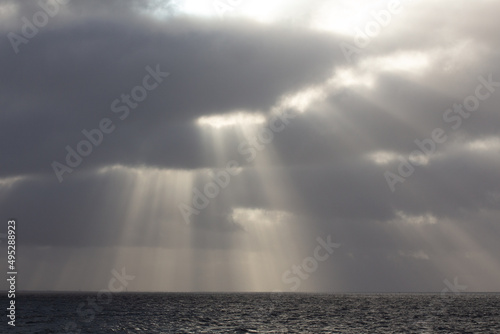 Dramatic clouds in the sky with sun beams over north sea with horizon