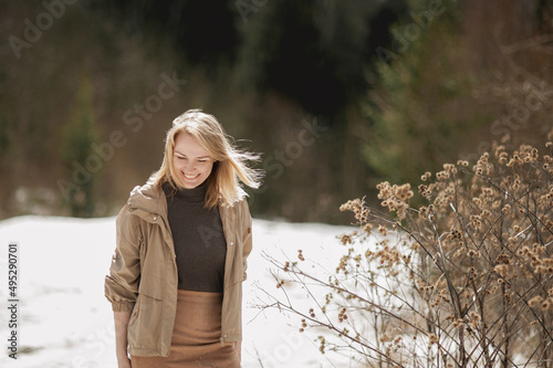 Portrait of a beautiful smiling blonde woman in a beige jacket walking on a sunny day in early spring. place for text