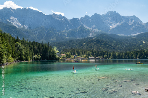 The german mountain lake Eibsee with clear water and people on their stand up paddle boards with the mountain Zugspitze in the background. photo