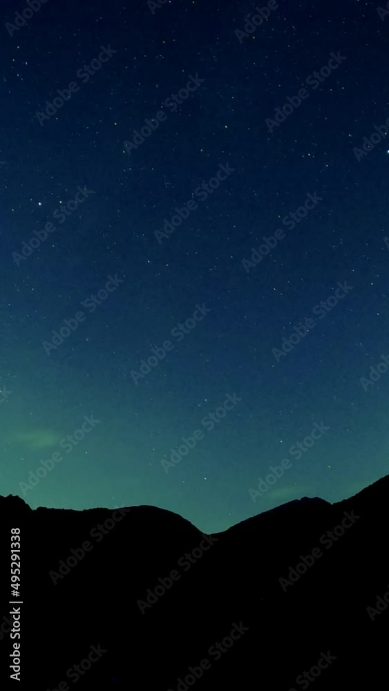 Timelapse of stars over silhouette mountains at night