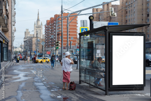 Vertical billboard at a public transport stop. Day, people. Mock-up.