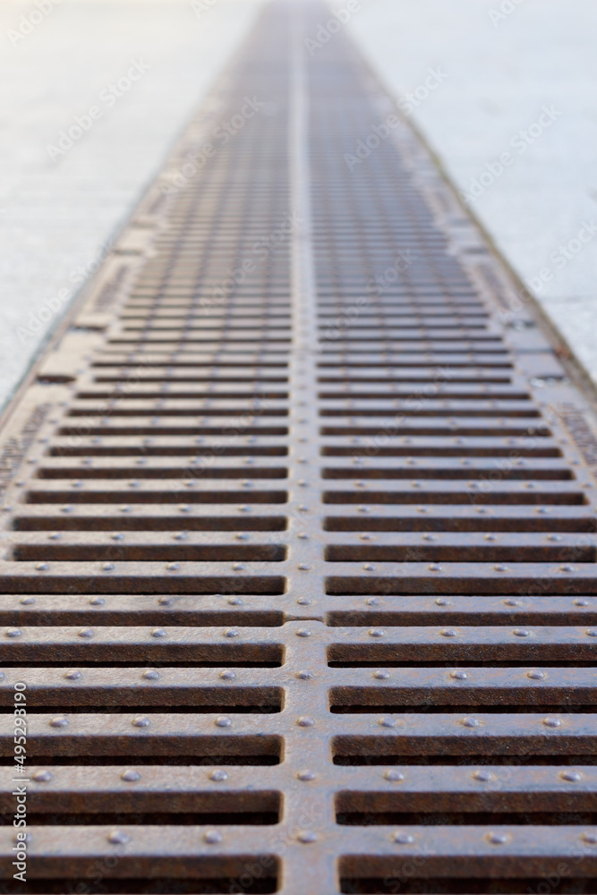 Steel rusty grating for drainage, rainwater runoff. Selective focus, perspective.