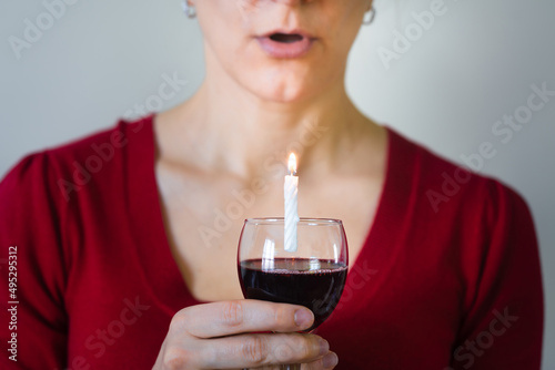 young beautiful woman keep a glass of wine with candle for selebrating birthday paty, close-up photo