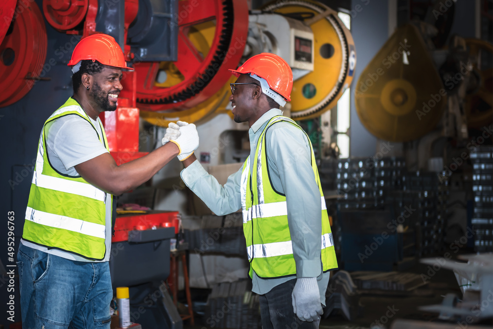 2 male worker African American, working in a factory, Shaking hands and happy that the work done together is successful, concept to teamwork of workers in industrial factories. 2 male worker African American, working in a factory, Shaking hands and happy that the work done together is successful, concept to teamwork of workers in industrial factories.