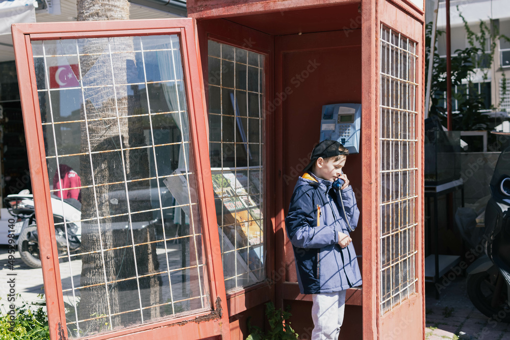 boy of European appearance in telephone booth is talking on the phone boy of European appearance in telephone booth is talking on the phone