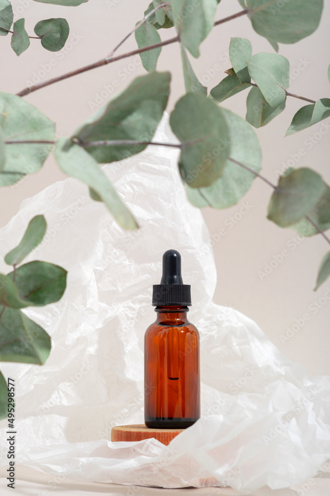Mockup cosmetic face serum brown glass bottle with a pipette on a stylish minimalist beige white background wooden pedestal. Eucalyptus branch. Female beauty concept, empty template Mockup cosmetic face serum brown glass bottle with a pipette on a stylish minimalist beige white background wooden pedestal. Eucalyptus branch. Female beauty concept, empty template