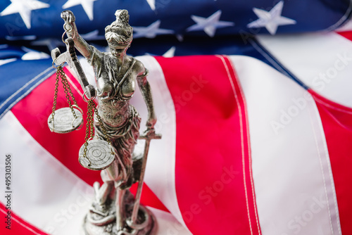 Sculpture of the goddess of justice - Themis against the background of the national flag of the United States of America. Justice, patriotism, rule of law, Independence Day.