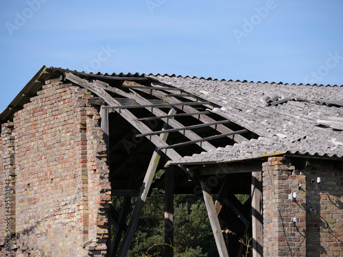 Detail eines mit Asbest-Dachwellplatten gedecktem und eingebrochenen Scheunendachs mit Dachbalken (Dachsparren) und Lattung photo