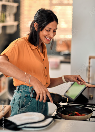 Olive oil, the good kind of fat. Shot of a happy young woman preparing a healthy meal at home.