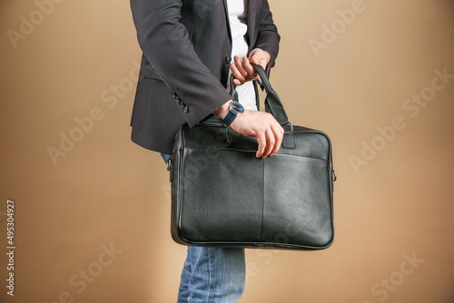 man holds leather briefcase close up, on brown background. Men's leather bag, studio photo shot