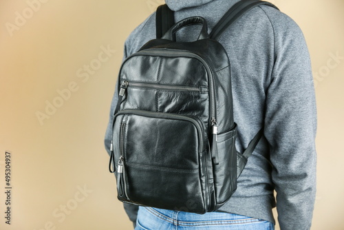 man wearing casual clothes with leather backpack studio photo shot on brown background.