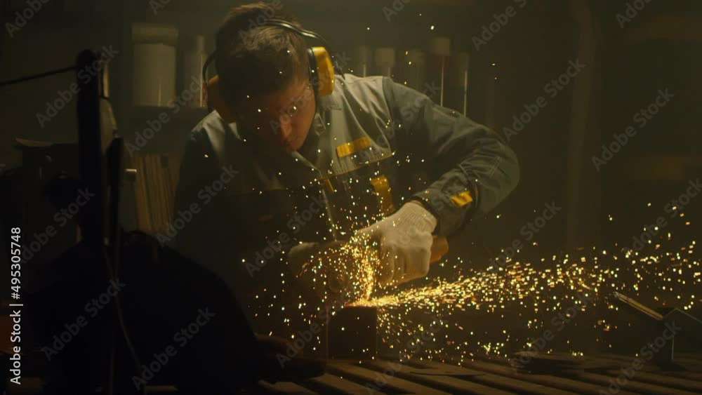 Industrial worker cutting metal with many sharp sparks. Male using special tool for cutting metal at workshop. Sparks flying from metal processing. Slow motion. 4K video. Shot on RED