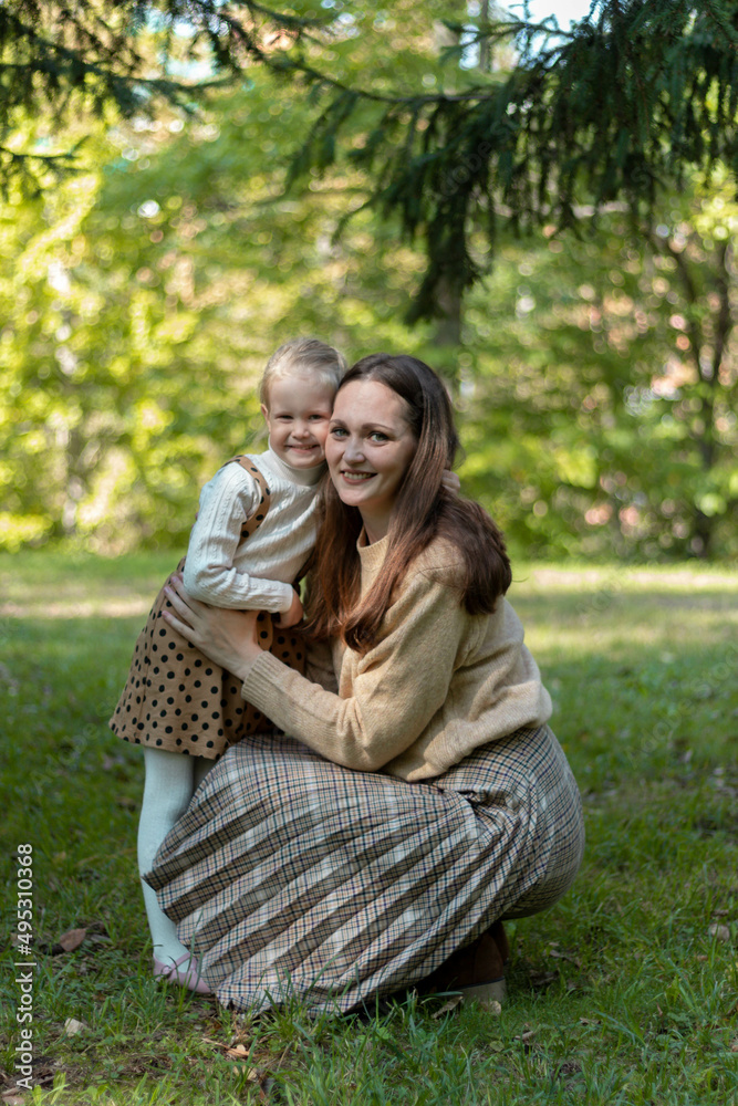 Mom and daughter are hugging in the park. Family walk. Happy mom and daughter. Green Park. Family values. Tenderness and love.