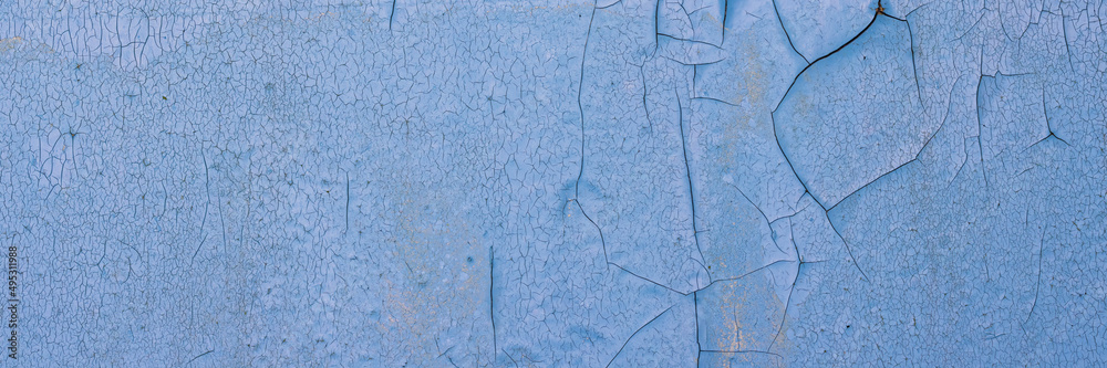 Peeling paint on the wall. Panorama of a concrete wall with old cracked flaking paint. Weathered rough painted surface with patterns of cracks and peeling. Wide panoramic texture for grunge background