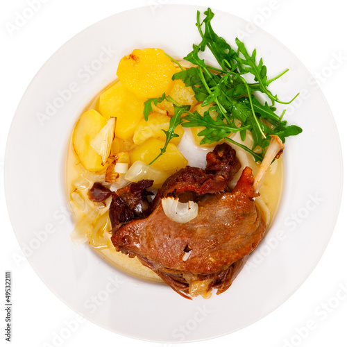 Just cooked portion of duck confit with fried poatoes. Isolated over white background photo