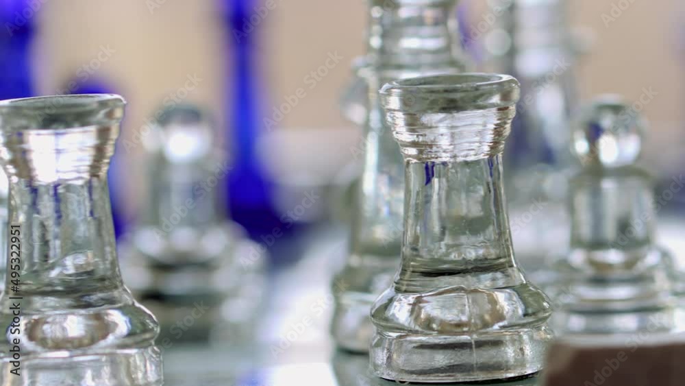 Transparent, glass chess board and its pawns, The camera rotates slowly around the game pawns.