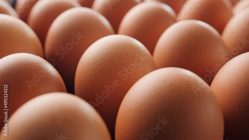 Lots of brown eggs - camera slide. Fresh chicken raw eggs in container. Close up, shallow depth. Egg production concept.