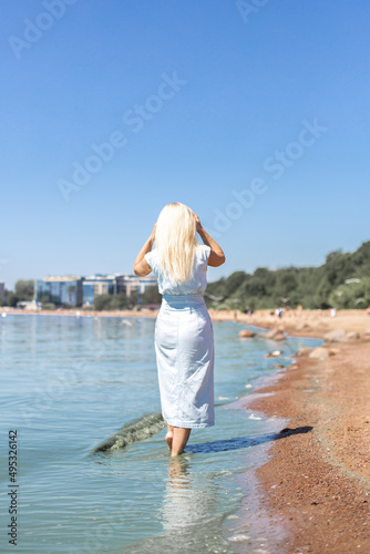  Young beautiful blonde hair woman in blue jeans dress looking at the sea 