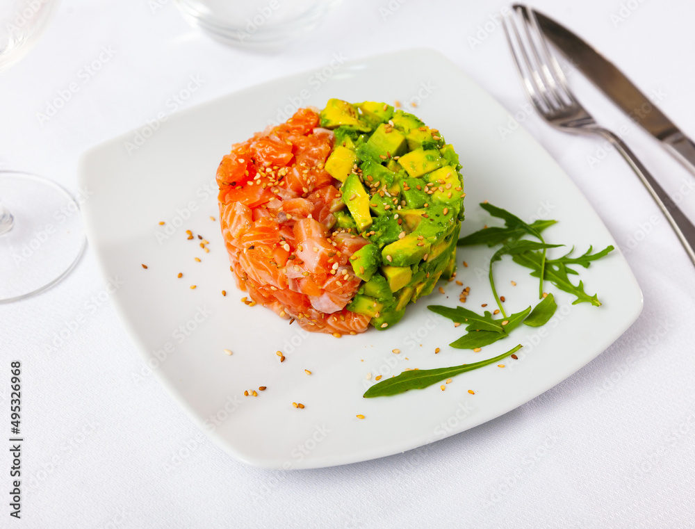 Traditional dish of French cuisine is salmon tartare with avocado, sprinkled with sesame seeds on top
