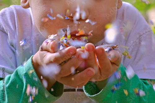 Niño soplando confeti que tiene en las manos