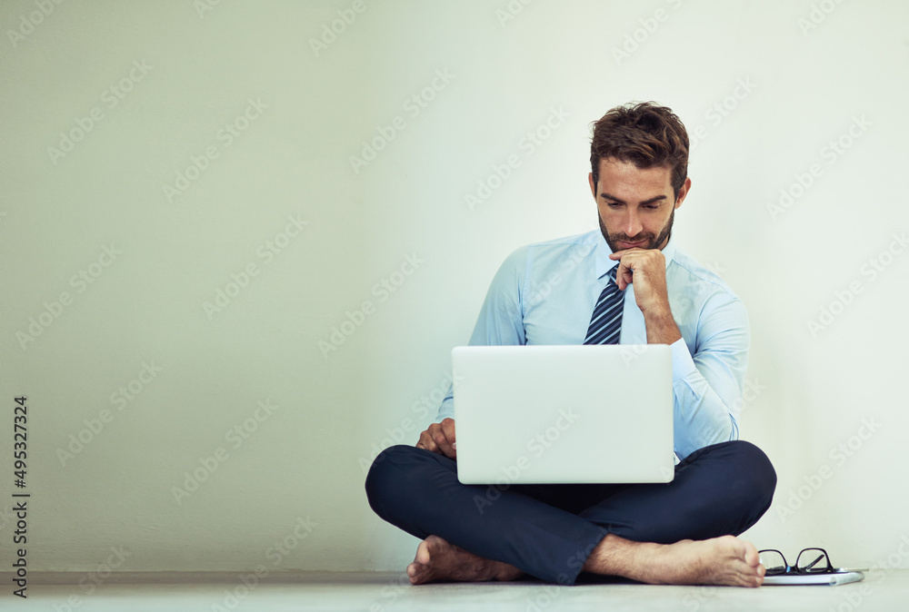 Hard work pays off. Shot of a young corporate businessman sitting on the ground with a laptop.