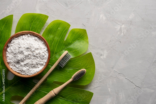 Bamboo toothbrushes and dentifrice or tooth powder made with natural ingredients on gray background photo