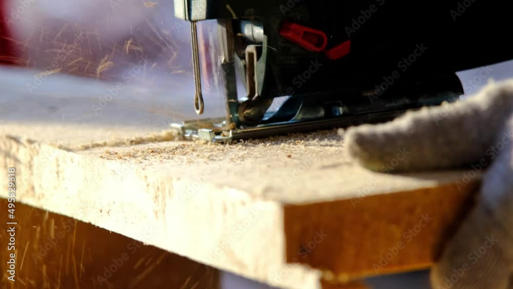 Sawing a board with an electric jigsaw in close-up. Carpentry on wood with a tool, sawdust flies, the saw cuts in a straight line. Home repair with your own hands, a sawmill. Slow motion Sawing a board with an electric jigsaw in close-up. Carpentry on wood with a tool, sawdust flies, the saw cuts in a straight line. Home repair with your own hands, a sawmill. Slow motion