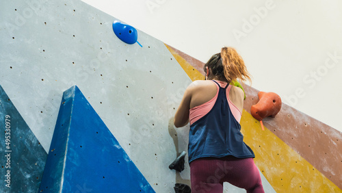 Unrecognizable woman climbing a wall in a gym.