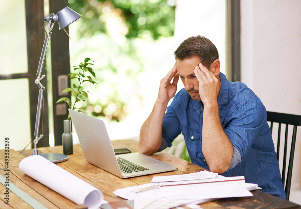 Theres just so much to do.... Shot of a man suffering from a headache while working from home. Theres just so much to do.... Shot of a man suffering from a headache while working from home.