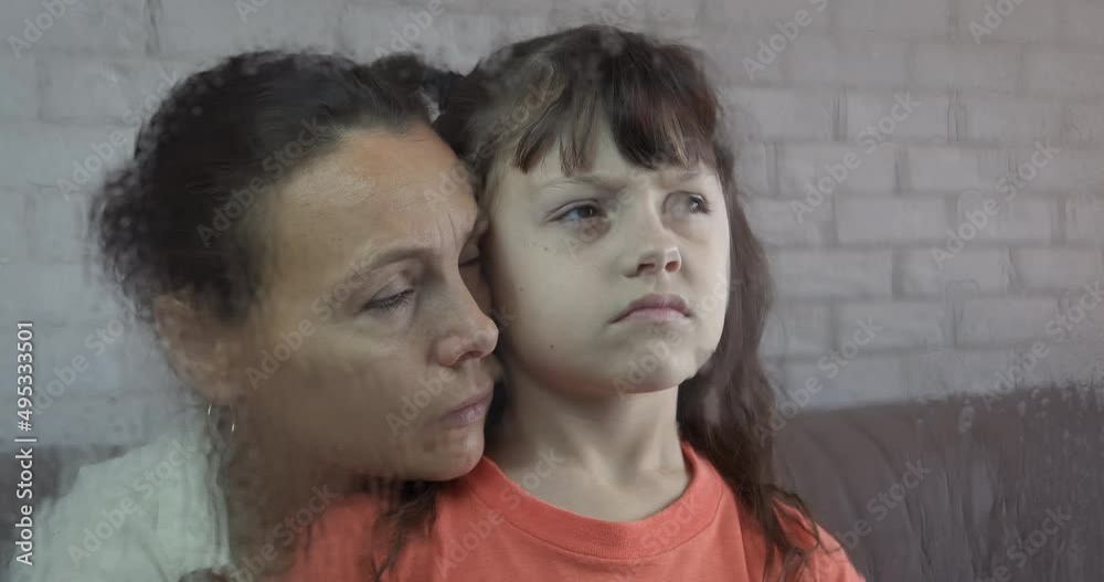 Family awaiting by window. A sad mother with child awaiting for somebody by the rainy glass in the room. Family awaiting by window. A sad mother with child awaiting for somebody by the rainy glass in the room.