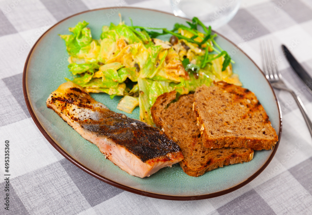 Baked salmon steak with crispy toasts and fragrant Mediterranean salad of lettuce with walnuts, pumpkin seeds and mustard vinaigrette