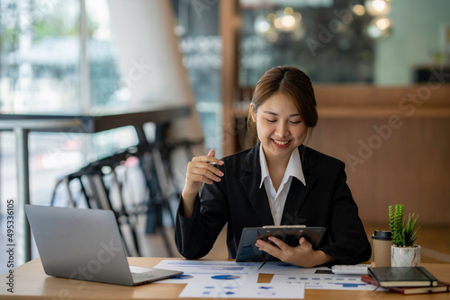 Happy Asian businesswoman laughing sitting at the work desk with laptop  a cheerful smiling female employee having fun feeling joy and positive emotion express sincere laughter at office workplace