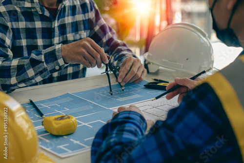 A team of young engineers and architects work, meet, discuss, design, plan, measure the layout of blueprints with tabletop tools in the Construction Concepts and Engineer's Offices.