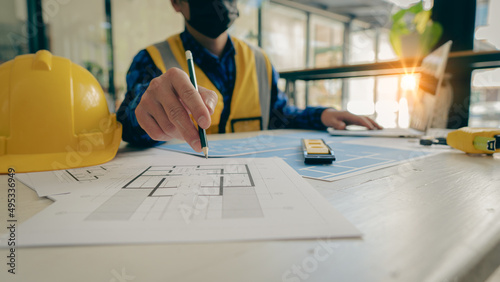 Young engineers and architects design, plan, measure the layout of blueprints with tabletop tools in construction concepts with hats and houses on the table.
