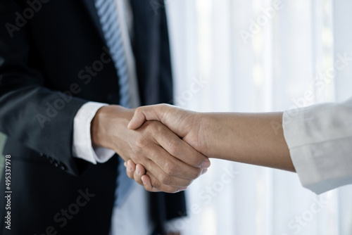 The businessmen and businesswoman shake hands after the meeting was successful and agreed upon