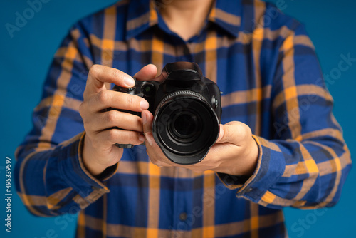 Photographer with a camera. Close-up of hand holding the digital camera while standing on a blue background