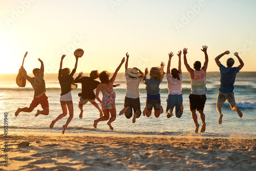 This is the best summer ever. Rearview shot of a group of young friends jumping into the air at the beach.