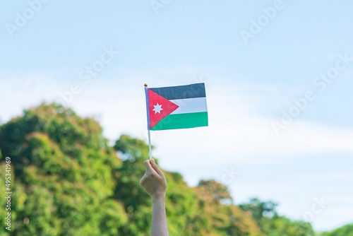 hand holding Jordan flag on nature background. Jordan Independence day and happy celebration concepts