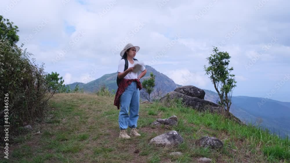 Hipster woman with backpack looking at a map on the background of mountains. Female hiker resting in nature and reading a map. Hipster woman with backpack looking at a map on the background of mountains. Female hiker resting in nature and reading a map.