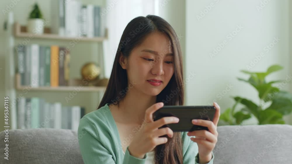 Smile young Asian woman using smartphone to play game and chatting in social media at home. Smile young Asian woman using smartphone to play game and chatting in social media at home.