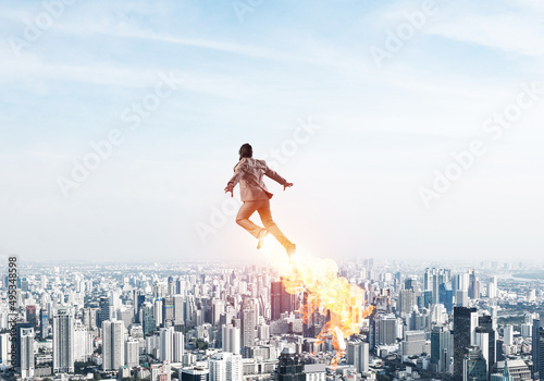 Businessman in suit and aviator hat flying in sky