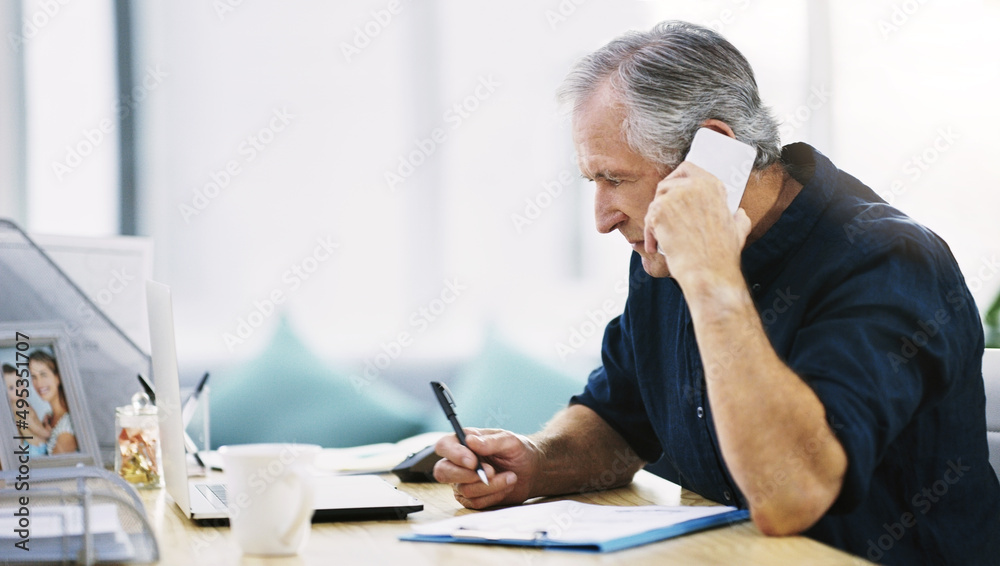 Handling business the best way he knows how. Shot of a mature businessman writing a few notes down while answering a phone call in his office. Handling business the best way he knows how. Shot of a mature businessman writing a few notes down while answering a phone call in his office.