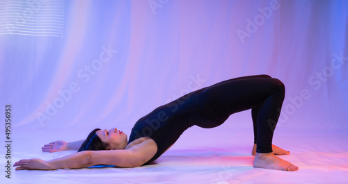 Athletic woman in high school, swimsuit and leggings, doing yoga, push-ups or push-ups, falancasana, plank pose variation, beautiful girl exercising at home or in a yoga studio