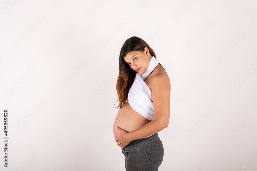 Portrait of a pregnant latin woman, touching her belly, with a relaxed and happy expression, on white background, copy space Portrait of a pregnant latin woman, touching her belly, with a relaxed and happy expression, on white background, copy space
