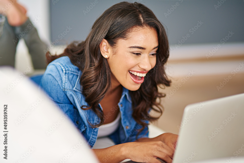 Social networking on the sofa. Cropped shot of an attractive young woman using her laptop while lying on the sofa. Social networking on the sofa. Cropped shot of an attractive young woman using her laptop while lying on the sofa.