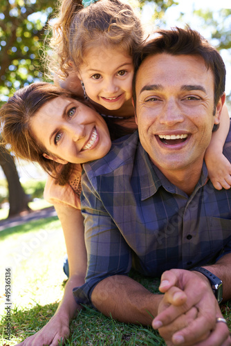 The happiest of families. Shot of a young family lying on the grass in the park.