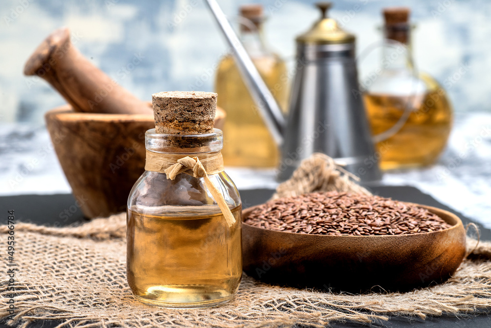 Glass bottle with linseed oil and flax seeds in a wooden bowl. Glass bottle with linseed oil and flax seeds in a wooden bowl.